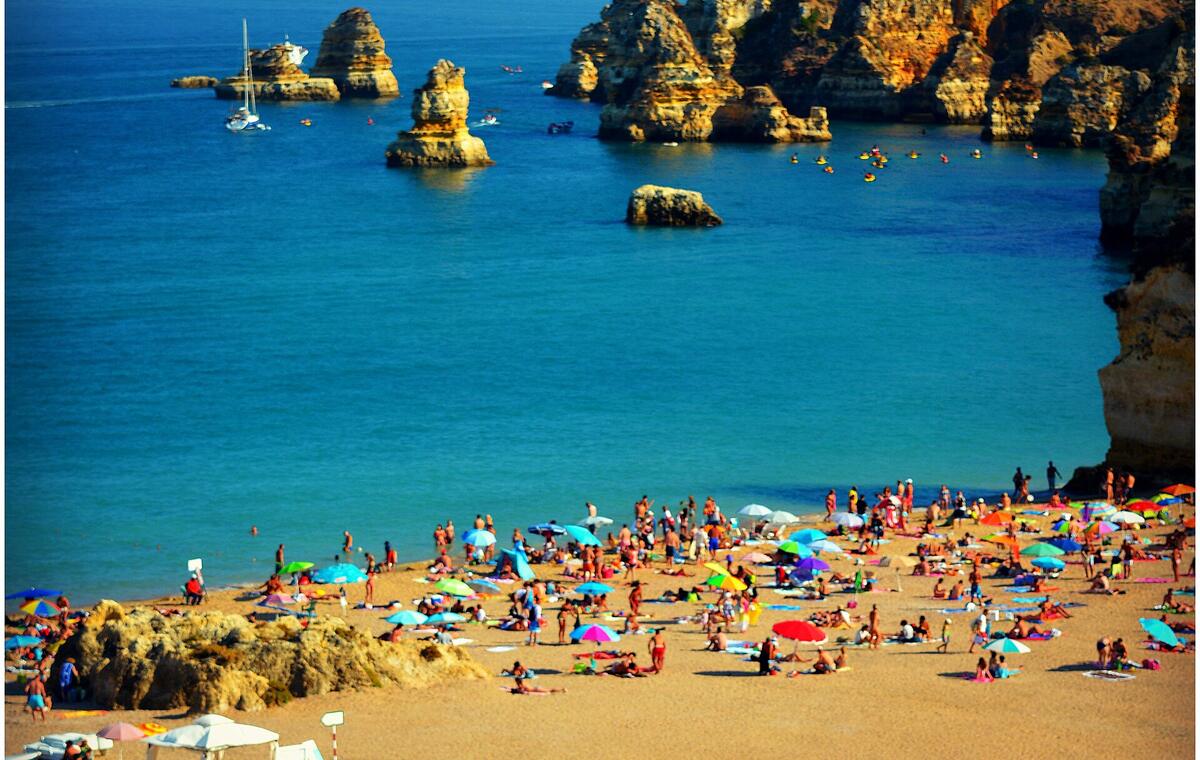 Sunbathers on a beach beside limestone cliffs near Lagos on Portugal's Algarve coast