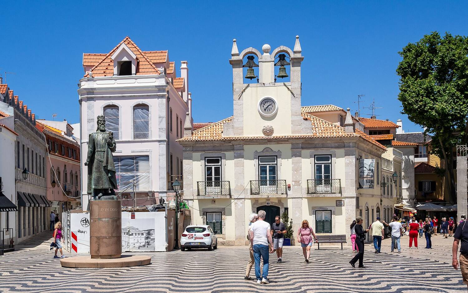 A whitewashed Portuguese townhouse with blue trim and terracotta rooftops on a quiet street