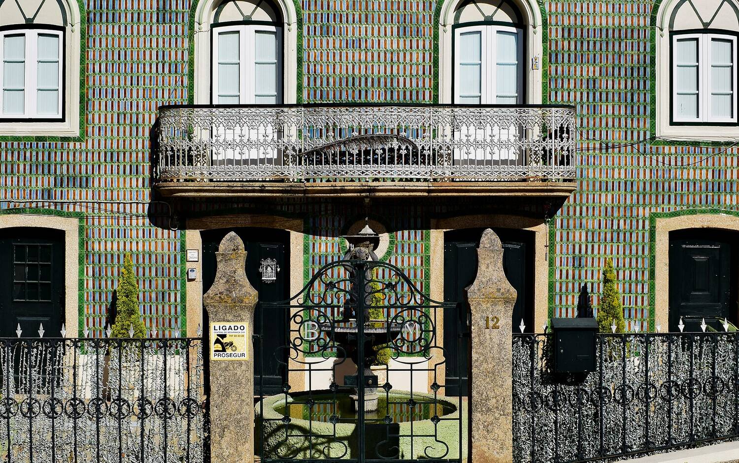 A pastel-coloured Portuguese townhouse with tiled azulejo walls and a for-sale sign outside
