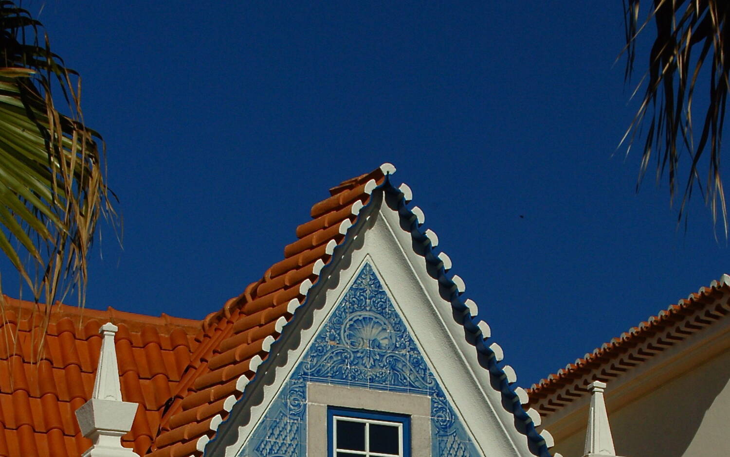A whitewashed Portuguese home with terracotta roof tiles and azulejo-tiled walls in the afternoon sun