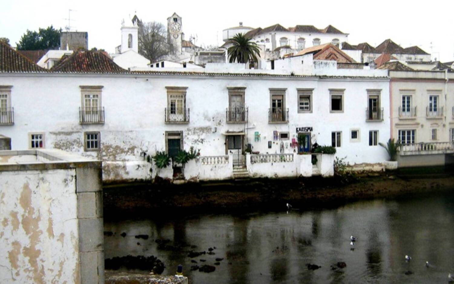 A surveyor inspecting the exterior wall and roofline of a traditional Portuguese villa